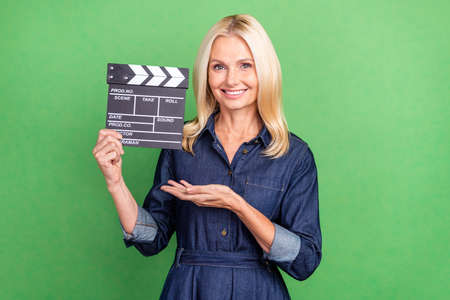 Photo of retired pretty lady advertise present clap board television shooting isolated over green color backgroundの写真素材