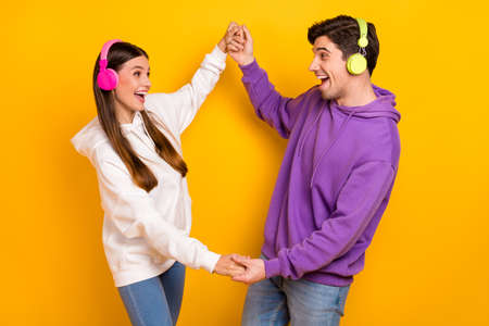 Photo of two crazy millennial people hold arms enjoy sound chilling free time isolated on yellow color backgroundの写真素材
