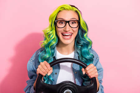 Portrait of attractive cheerful wavy-haired girl holding steering wheel having fun isolated over...
