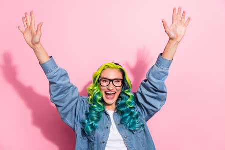 Photo of impressed funky young bright lady dressed denim jacket glasses rising arms smiling isolated pink color backgroundの写真素材