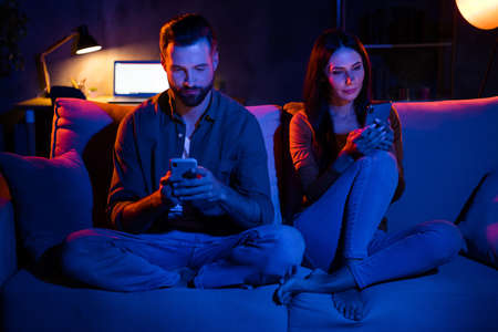 Photo of spouses friends lady guy sit cozy divan use smart app search website sale in late dark...