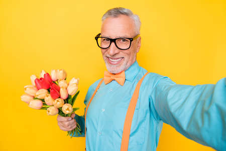 Photo of sweet funny retired man wear turquoise shirt suspenders tacking selfie holding flowers...