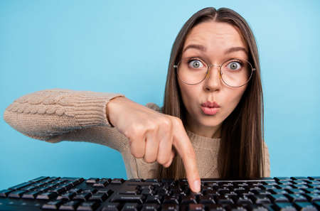 Portrait of attractive trendy amazed funny girl typing texting chatting pressing button pout lips isolated over bright blue color backgroundの写真素材