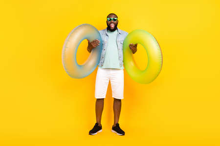 Full length body size view of attractive trendy crazy cheery guy holding life buoy rest relax isolated over bright yellow color backgroundの写真素材