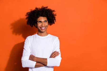 Photo of pretty attractive guy dressed white shirt arms crossed looking empty space isolated orange...
