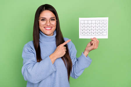 Photo of nice millennial brunette lady index paper wear blue pullover eyewear isolated on green color backgroundの写真素材
