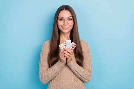 Portrait of attractive cheerful girl holding in hands meds anti virus pharmacy isolated over bright blue color backgroundの写真素材