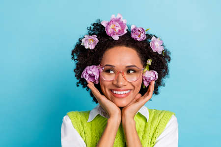 Portrait of cute lady in casual clothes look empty space daydreaming have flowers in hair isolated on blue color backgroundの写真素材