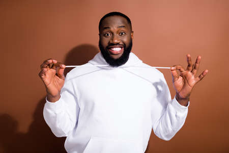 Photo of silly carefree guy wear white hoodie smiling preparing for party isolated brown color backgroundの写真素材