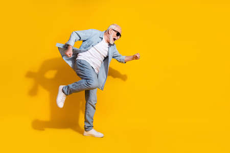 Full length body size view of attractive cheerful crazy grey-haired man having fun great success isolated on bright yellow color backgroundの写真素材