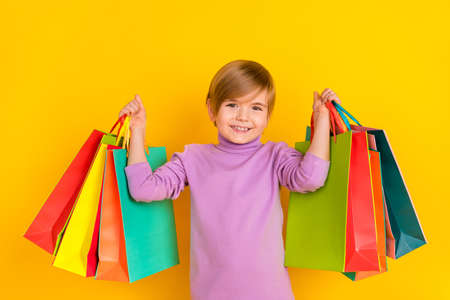 Photo of cute adorable small kid little boy son go shopping to buy mom present for birthday isolated on yellow color backgroundの写真素材