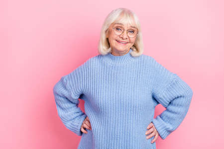 Photo of pretty lady granny hands on waist knitwear pullover eyewear isolated over pink color backgroundの写真素材