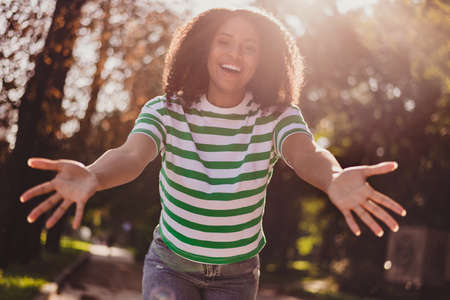 Photo of young adorable african woman good mood open arms cuddle hospitable wear casual outfit outdoorsの写真素材