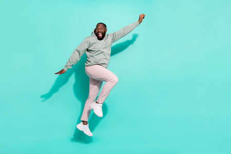Full length body size view of attractive cheerful active guy jumping striving isolated over bright teal turquoise color backgroundの写真素材