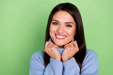 Portrait of attractive cheerful brown-haired woman wearing cosy comfy warm clothes isolated over bright green color backgroundの写真素材