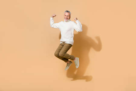 Full length body size view of attractive cheerful lucky man jumping self concept isolated on beige...