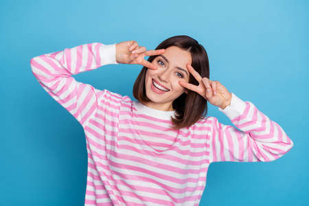 Photo of lovely young bob hairdo lady show v-sign wear striped shirt isolated on blue color...