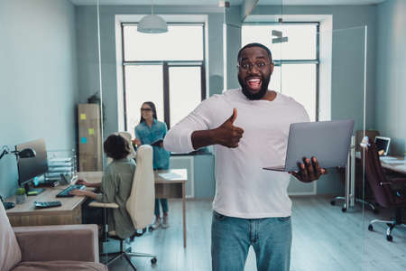 Portrait of handsome beautiful cheerful group guy using laptop showing thumbup project at workplace workstation indoors.の写真素材