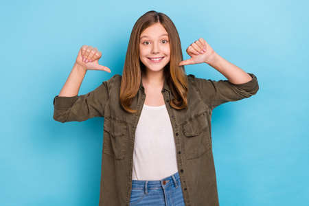 Photo of beautiful cheerful teenage woman point thumbs herself choose me promoting isolated on blue...