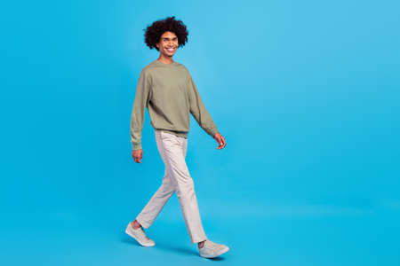 Full body profile side photo of youth cheerful man walk vacation isolated over blue color backgroundの写真素材