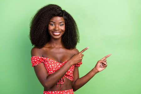 Photo of lovely millennial curly hairdo brunette lady index empty space wear red cloth isolated on green color backgroundの写真素材