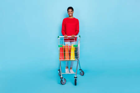 Full size photo of good mood nonbinary man go shopping buy present for family isolated on blue color...