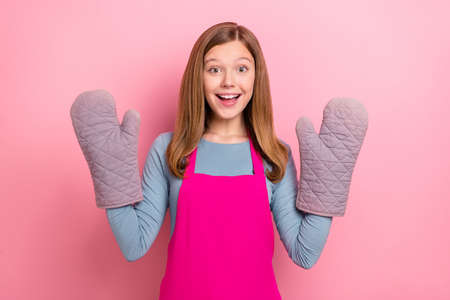 Portrait of attractive cheerful funny girl wearing apron gloves domestic culinary isolated over pink pastel color background.の写真素材