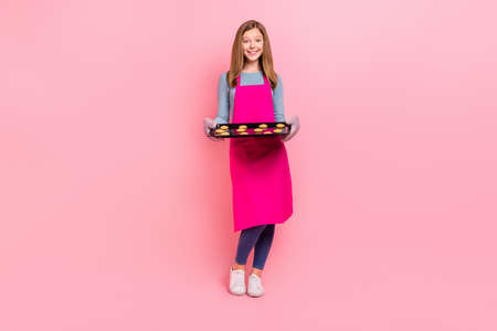 Full length body size view of attractive trendy cheery girl holding tray domestic baked cookies isolated over pink pastel color backgroundの写真素材