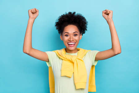 Photo of young excited african girl rejoice victory success triumph fists hands isolated over blue color backgroundの写真素材