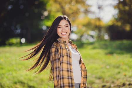 Photo of sweet adorable young lady wear checkered shirt smiling walking outdoors forest clearing