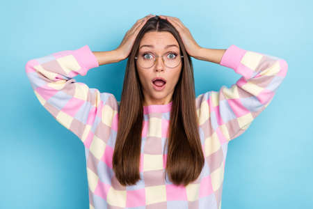 Photo of shocked surprised lady unbelievable news concept wow face wear specs sweater isolated blue color backgroundの写真素材