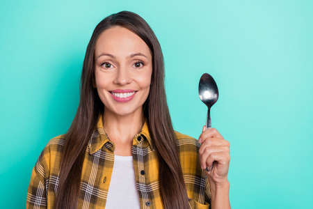 Photo of cute young brunette lady eat wear yellow shirt isolated on turquoise color backgroundの写真素材