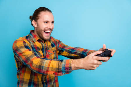 Photo of cool millennial tail hairstyle guy playstation look empty space wear plaid shirt isolated on blue color backgroundの写真素材