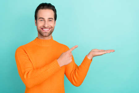 Portrait of positive man finger direct hand palm hold empty space isolated on teal color background