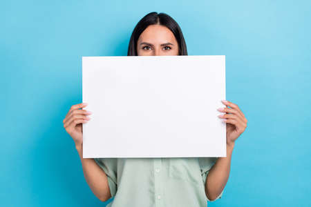 Photo of young woman cover mouth paper banner advertising promoter isolated over blue color backgroundの写真素材