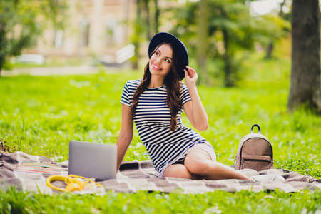 Portrait of beautiful dreamy cheerful schoolgirl doing home task work project sitting on cover on fresh air outdoorsの写真素材