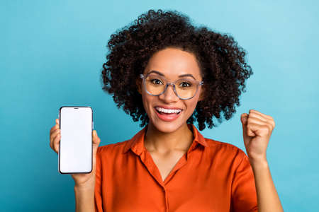 Portrait of attractive trendy lucky cheery wavy-haired girl holding gadget copy space isolated over...