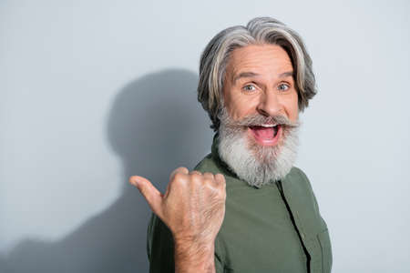 Portrait of attractive cheerful lucky grey-haired man demonstrating copy empty space solution...