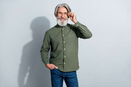 Portrait of attractive cheerful skilled experienced grey-haired man touching specs isolated over gray pastel color backgroundの写真素材