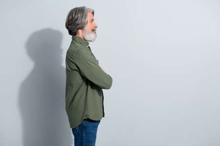 Profile side view portrait of attractive grey-haired man copy empty blank space folded arms isolated over gray pastel color backgroundの写真素材