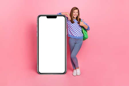Full size photo of funky girl thumb up recommend cellphone offer wear backpack isolated pink color...