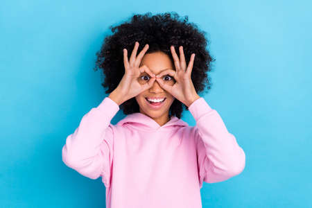 Portrait of attractive cheerful trendy bushy haired funky girl showing ok-sign like glasses isolated...