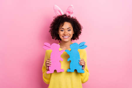 Photo of dreamy excited lady wear yellow sweater easter headband holding two bunnies isolated pink...