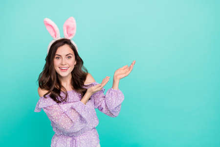 Portrait of attractive cheerful girl wearing ears holding copy space promo ad isolated over bright...