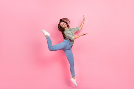 Full length photo of sweet millennial brunette lady jump wear outfit jeans sneakers isolated on pink color backgroundの写真素材