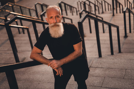 Photo of serious concentrated pensioner coach man stand strong stairs wear t-shirt urban town...