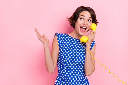 Photo of impressed young brunette lady talk telephone wear blue blouse isolated on pink color backgroundの写真素材