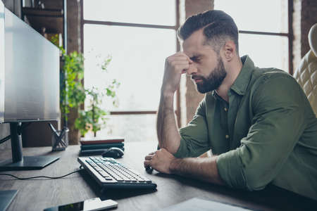 Profile side view portrait of attractive tired guy writing solving task developing project touching nose at work place station indoorsの写真素材