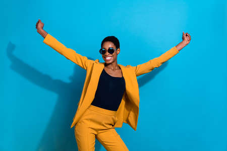 Portrait of positive cool person raise arms beaming smile have good mood isolated on blue color...