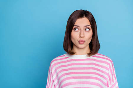 Photo of dreamy funny lady dressed pink pullover lips pouted looking empty space isolated blue color backgroundの写真素材